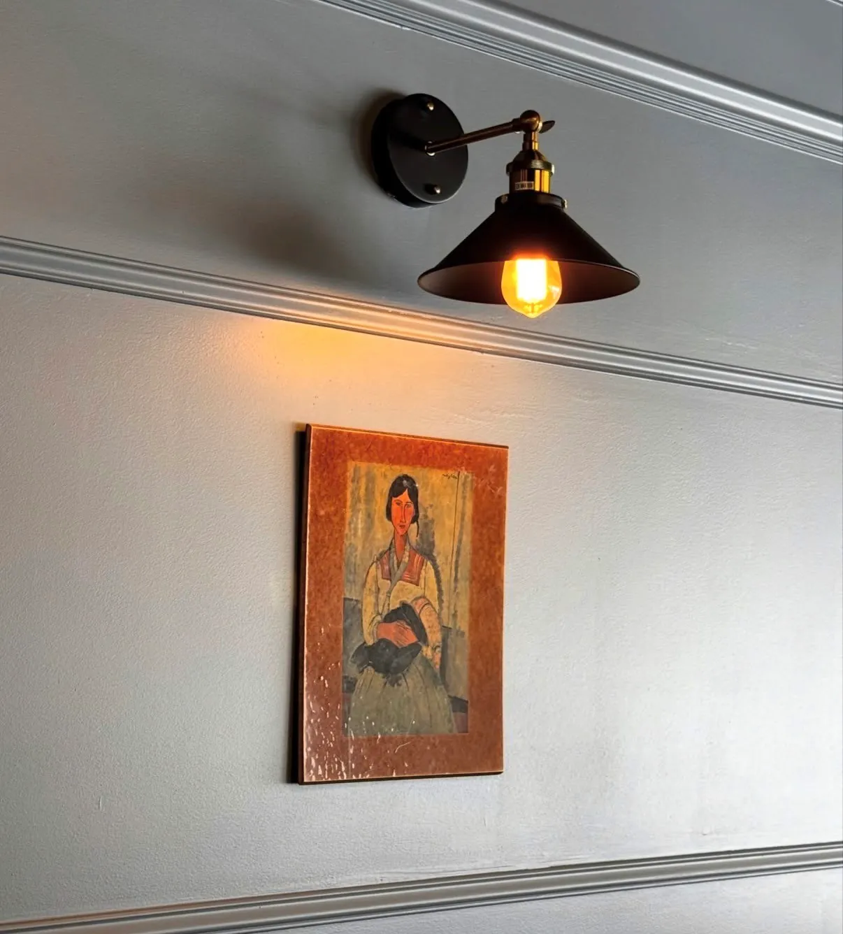Wall sconce above a framed portrait painting in the shop