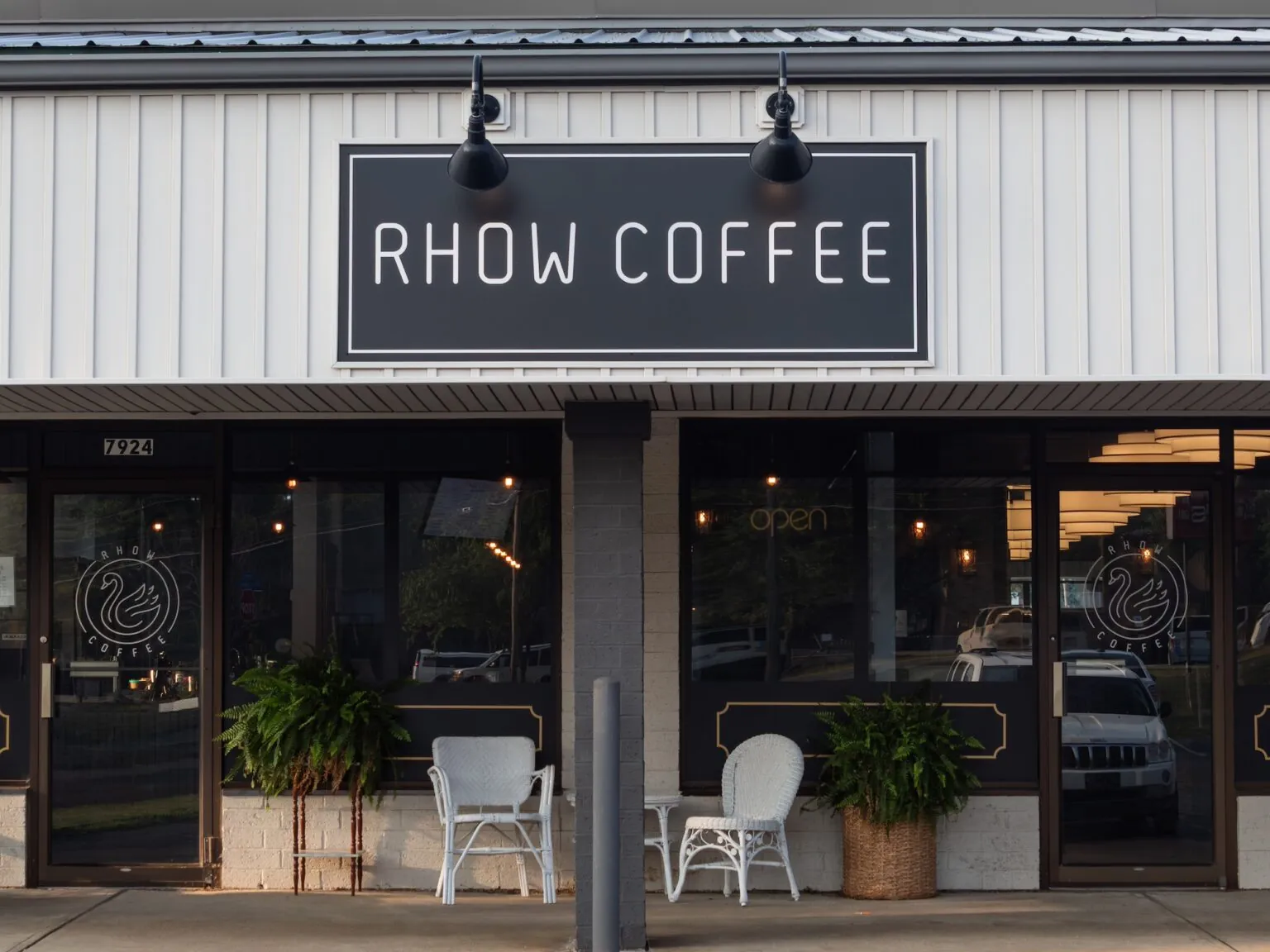 RHOW Coffee storefront with the wordmark sign above the entrance and the swan badge on the windows